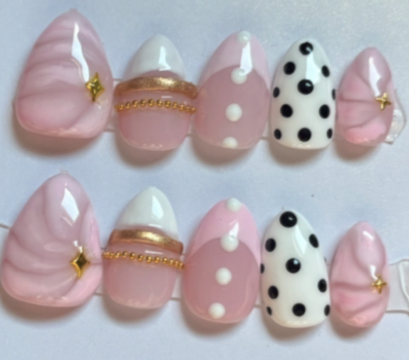 Pink swirl nails with gold charms and black polka dots
